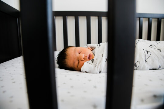 Newborn baby sleeps soundly in his crib