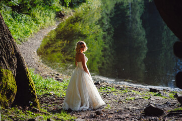Bride in white wedding dresses on rocky shore near lake in mountains. Wedding on a background of mountain landscape. Picturesque view of the mountain.