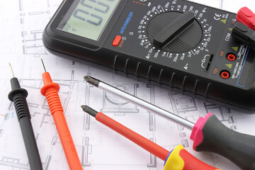 Multimeter and tools for electrical installation in a close-up schematic diagram.