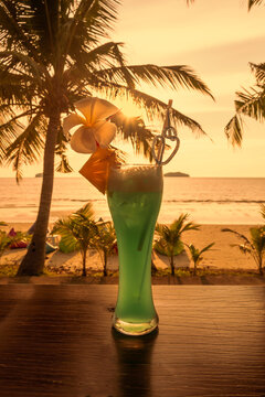 Refreshing cocktail on the background of an orange tropical sunset. Relaxing evening. Summer, exotic vacations.