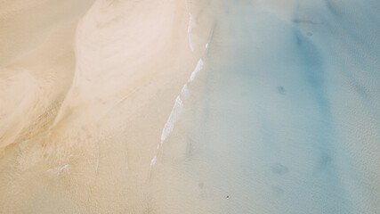 Vertical view of sand and beach with blue clean sea water. Tropical aerial landscape with waves and ocean. Seascape and amazing travel destination concept. Summer holiday vacation