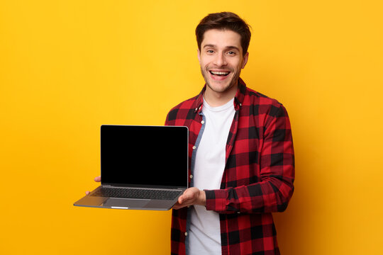 Happy young man showing black empty laptop screen