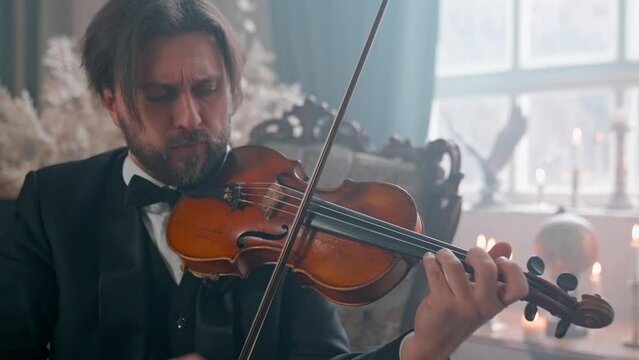 A Young Girl And Man Plays The Violin In A Beautiful Retro Room With Flowers And A Piano.
