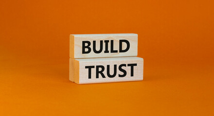 Build trust symbol. Concept words Build trust on wooden blocks on a beautiful orange table orange background. Business and build trust concept, copy space.