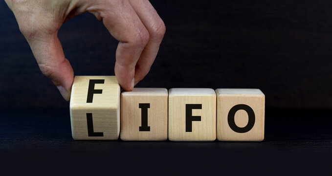 LIFO or FIFO last in first out symbol. Changes concept words LIFO to FIFO on wooden blocks. Beautiful grey table grey background. Businessman hand. Business LIFO or FIFO concept. Copy space.