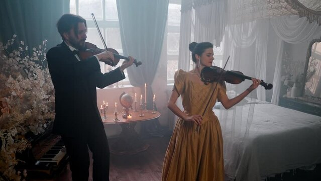 A Young Girl And Man Plays The Violin In A Beautiful Retro Room With Flowers And A Piano. 