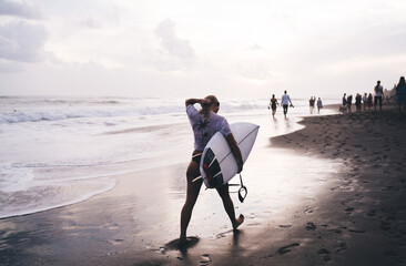 Back view of sportive female spending time for catching large waves and getting adrenaline during...