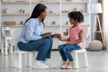 Adorable african american little girl having session with child psychologist