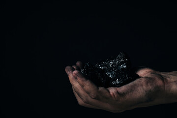 Dirty hands miner holding coal.Heavy coal mining.