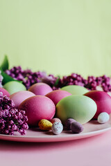 Close-up of beautiful lilac Easter eggs with blooming lilac branches. Easter decor. Selective focus.