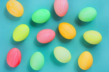 multi-colored eggs in pastel tones on a green background. Easter decor. top view.