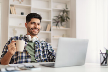 Arab man using laptop drinking coffee office
