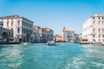 Fototapeta na wymiar Motorboat floating on clear waters of Grand Canal in romantic Venice during bright summer daytime, landscape with ancient architecture buildings located in historic center of Italian city