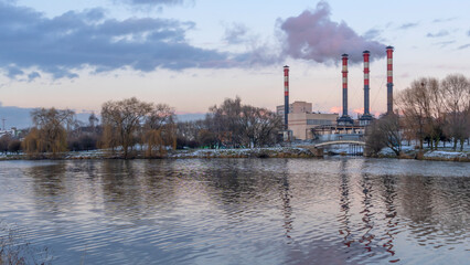 Obraz na płótnie Canvas Power station with reservoir in winter. Beautiful seaside winter sunset with a smoking factory chimney.