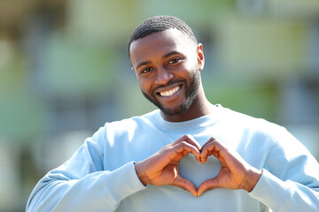 Happy man with black skin doing heart shape