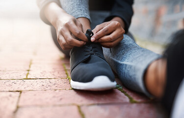 Time to move. Cropped shot of a woman tying her shoelaces before a workout session.