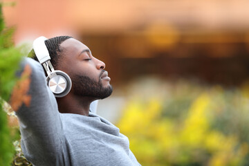 Man with black skin relaxing listening to music in a park