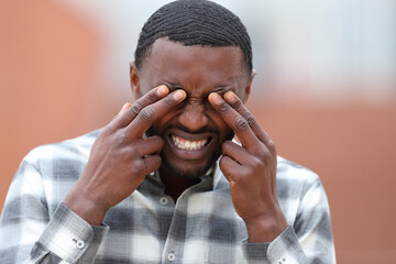 Man with black skin scratching eyes in the street