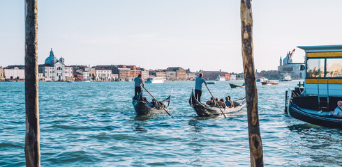 Tourists travelling on gondola transport in lagoon grand canal for exploring Venice Italy during summertime vacations, people visiting Venezia during romantic holidays for recreating on excursion