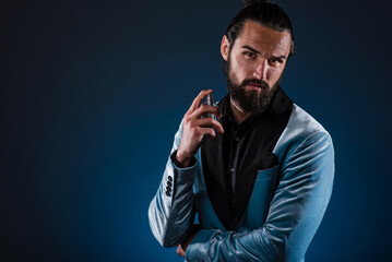 Masculine bearded young man holding a generic bottle of perfume. Male fragrance and perfumery, cosmetics. Masculine perfume. Bearded man holding a bottle of perfume