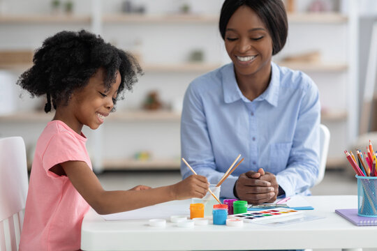 Creative african american little girl painting with child specialist