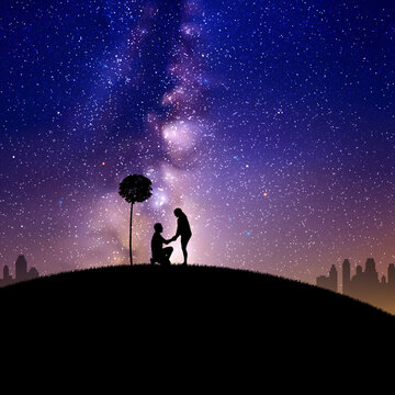 Lovers under tree at park. Marriage proposal. Milky Way at night sky