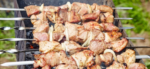 Marinated shashlik preparing on a barbecue grill over charcoal. Traditional Russian shashlik on a barbecue skewer