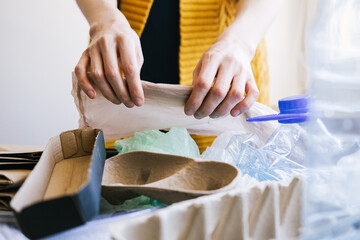Unrecognizable woman sorting garbage in her kitchen.