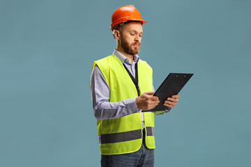 Male engineer wearing a reflective vest and helmet holding a clipboard
