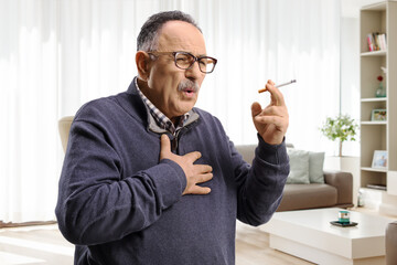 Mature man smoking and coughing at home