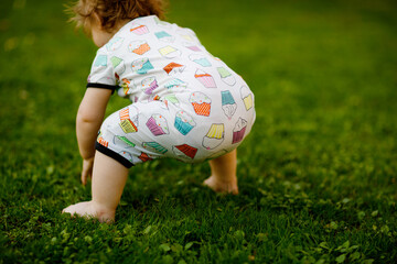 Cute adorable baby girl crawl and make first steps outdoors. Healthy happy toddler child learning...