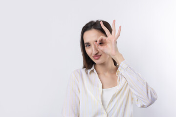 Close up portrait of attractive quirky young woman making binoculars with hands showing ok gesture on white studio background.