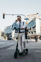 Young modern man using and driving electric scooter on city street. Modern and ecological transportation concept.