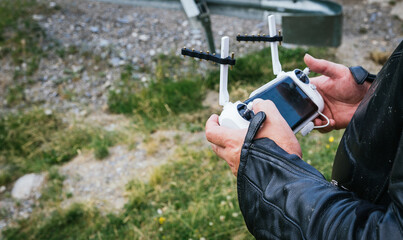 hands of a motorcyclist controlling a drone's white controller