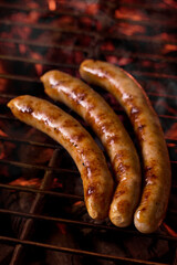 Three sausages on the grill. Photo of food on a dark background