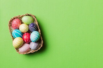 Multi colors Easter eggs in the woven basket on colored background . Pastel color Easter eggs. holiday concept with copy space
