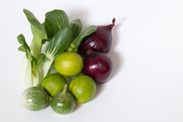 closeup a group of vegetable thai eggplant, limes, bok choy or cantonese vegetables, red onions isolated on white background. harvest organic tropical food