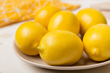 Fresh cutted lemon and whole lemons over round plate on colored background. Food and drink ingredients preparing. healthy eating theme top view vith copy space