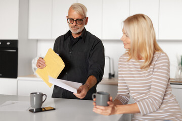 Mature man reads letter paper. Family budget of a mature couple, bankruptcy. Sanctions, increased rent.