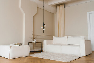 Scandinavian interior with a light sofa on a wooden parquet floor, a wooden side table and beige walls