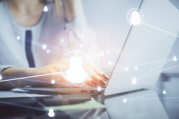 Double exposure of woman hands typing on computer and social network theme hologram drawing. People...