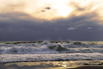Dramatic sea landscape of stormy sea under dark sky at sunset. Strong waves lapping the shore.