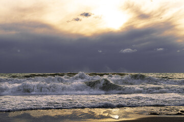 Dramatic sea landscape of stormy sea under dark sky at sunset. Strong waves lapping the shore.