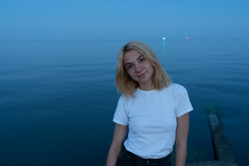 Fototapeta na wymiar Young blonde woman on a rocky seashore after sunset. Odessa. Ukraine.