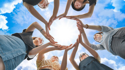 Friends make a circle from their palms against the background of a fabulous sky.