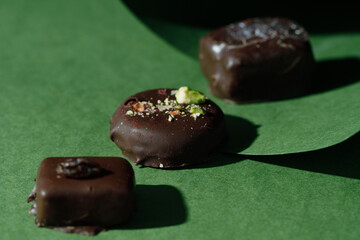 A set of handmade dark chocolate candies on a green background. Concept design. Fashionable design. Dark style.