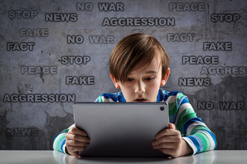 A cute child watches military news in the basement against the background of a wall with inscriptions. Breaking News about the war. watch the Breaking news in the basement