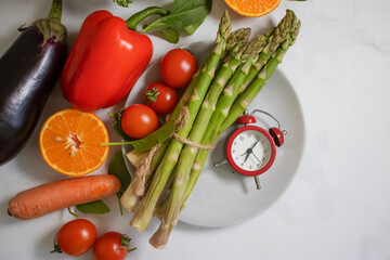 Fresh different vegetables, alarm clock background