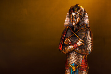 Egyptian pharaoh figurine in orange smoke on a black background.