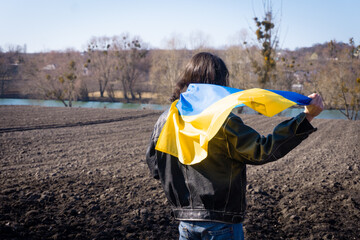 young man covered with the flag of ukraine in the field. patriot